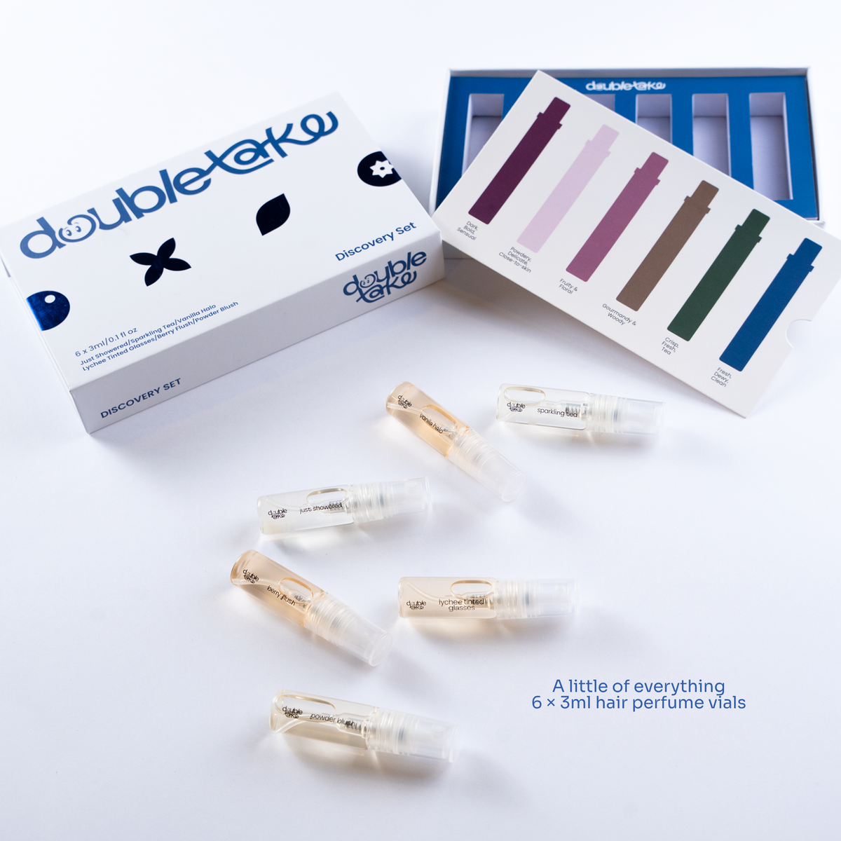 Double Take hair discovery set showing six 3ml hair perfume vials, a white and blue product box, a sample card with color swatches, and all the vials arranged on a white background with text reading 'A little of everything 6 x 3ml hair perfume vials'.